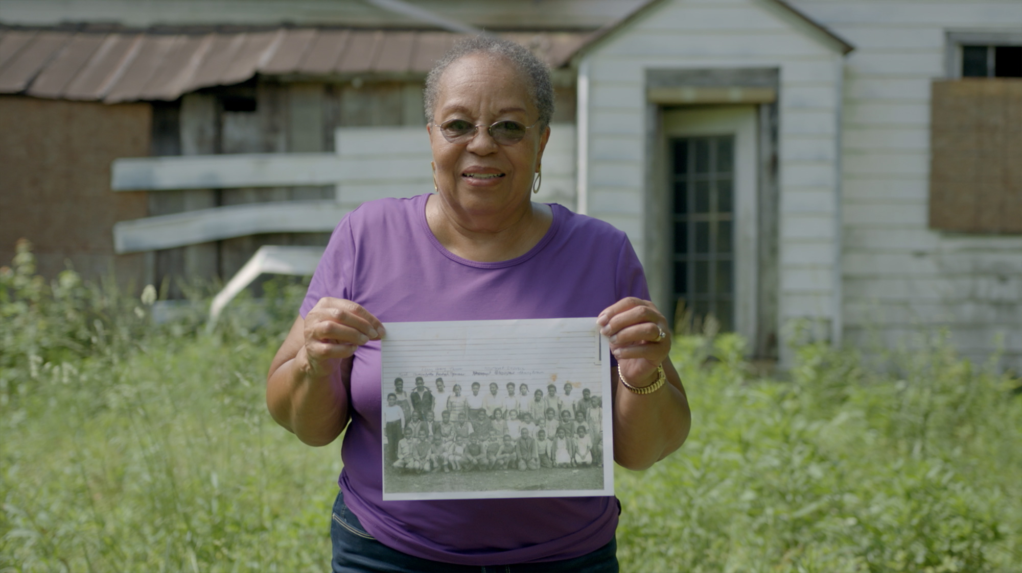 former rosenwald student now elderly woman holds up old school photo